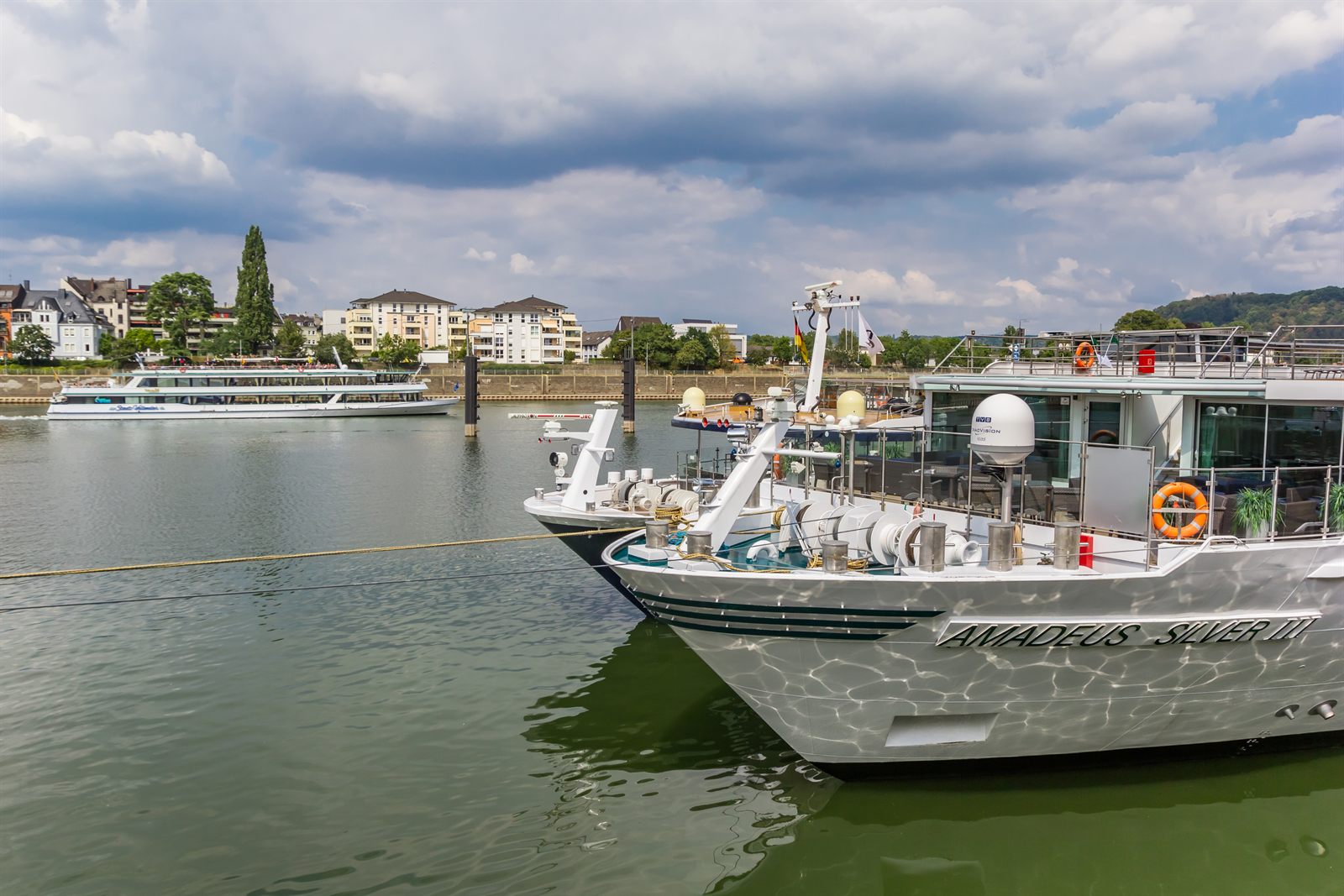 Bow of a river cruise ship moored on the Rhine with another ship passing behind