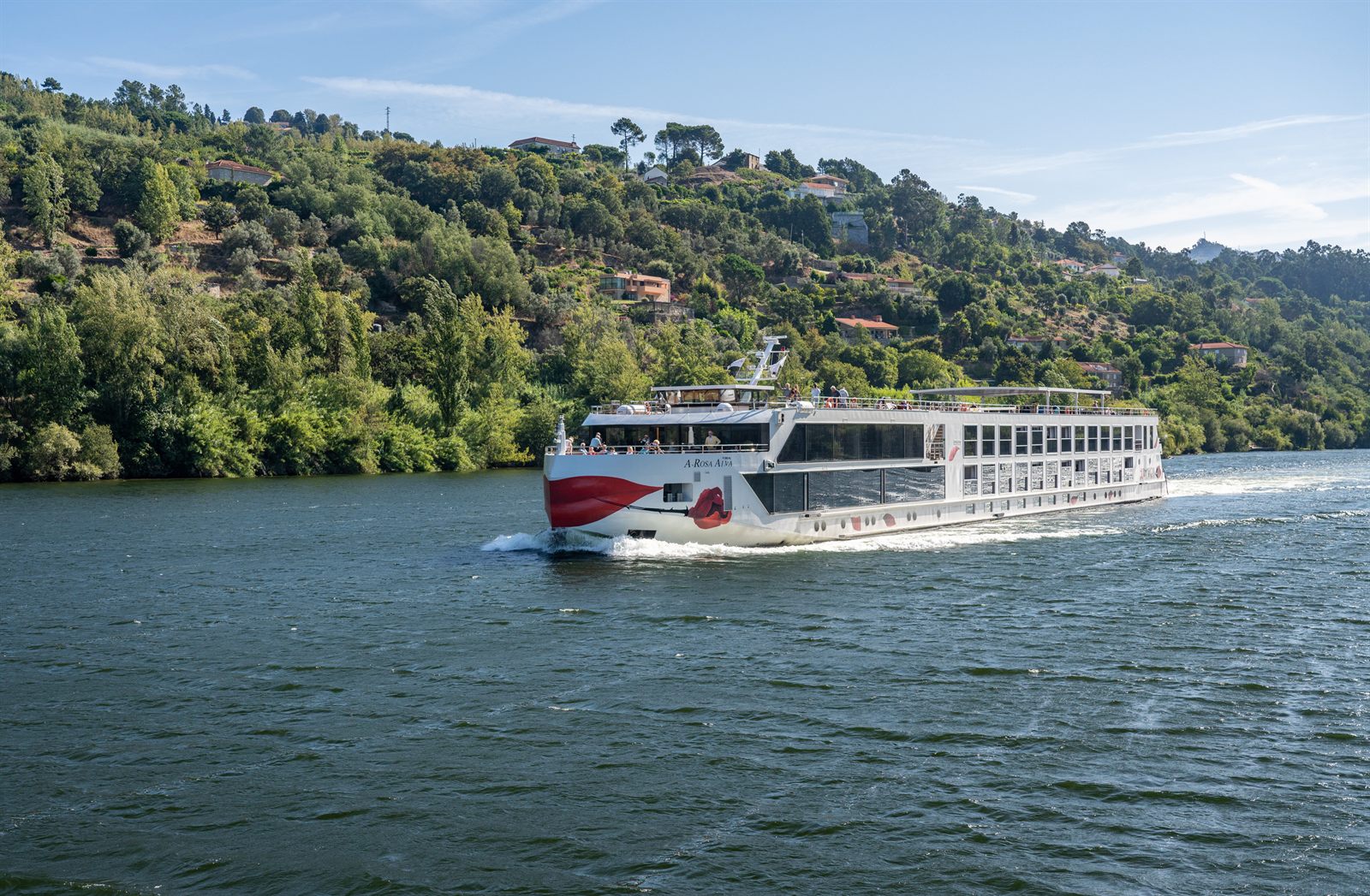 River cruise ship sailing the Douro River between green hills in Portugal
